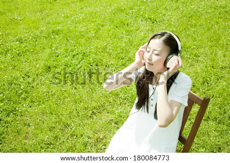 Japanese woman sitting and listening to music outdoors