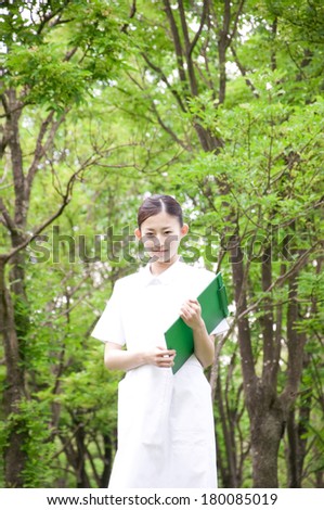 Japanese nurse standing with a clipboard in the woods
