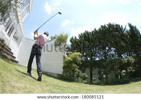 Rear View of senior Japanese man practicing golf swing