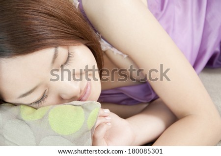 Japanese woman lying on the sofa and smiling in her sleep