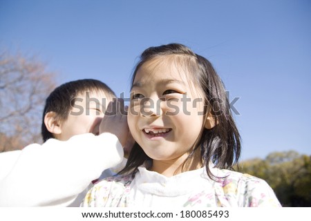 Primary school boy whispering into a female classmate\'s ear