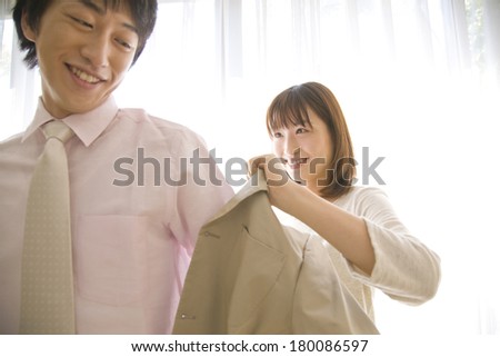Japanese Wife putting a suit jacket on husband