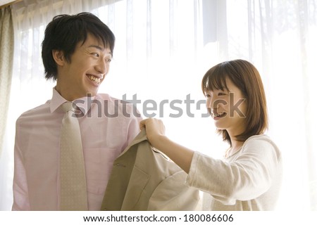 Japanese Wife putting a suit jacket on husband