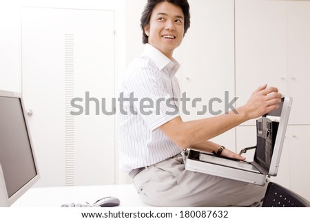 Japanese Businessman opening the bag sitting on top of the desk