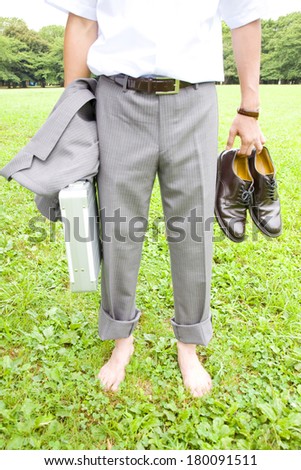 Lower body of Japanese businessman standing on the grass barefoot