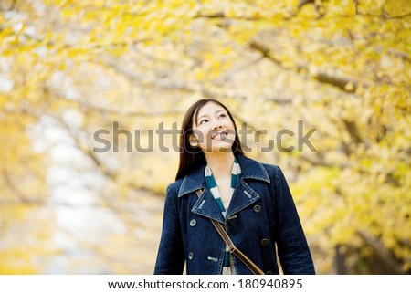 Japanese woman walking while looking up at the ginkgo