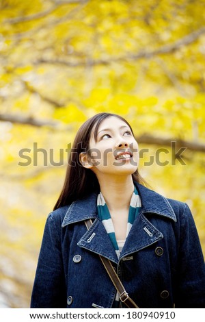 Japanese woman walking while looking up at the ginkgo