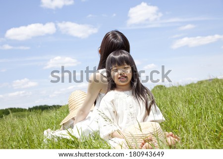 Young girls and Japanese woman to sit back to back in the grassland