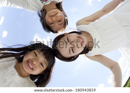 Young Japanese woman and two girls smiling in a circle