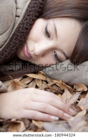 Japanese woman laying on a pile of leaves,