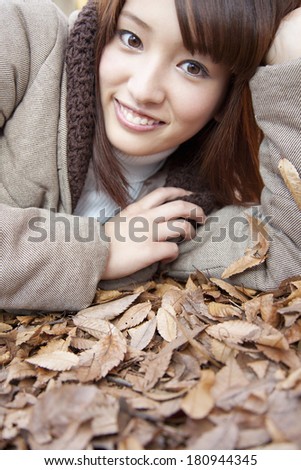 Japanese woman laying on a pile of leaves,