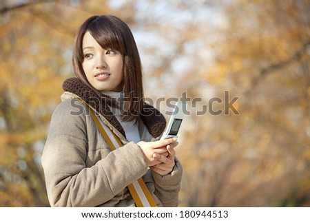Japanese woman looking back, with a mobile phone on her hand,