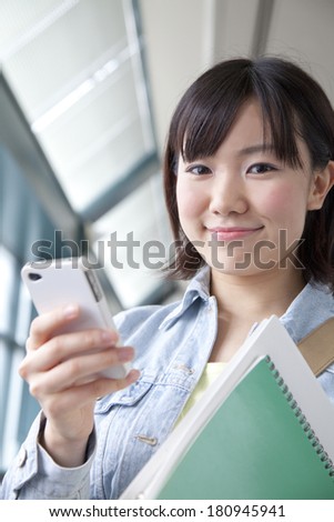 A Japanese student smiling while holding a smartphone,
