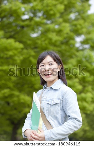 A Japanese student smiling at the green environment,