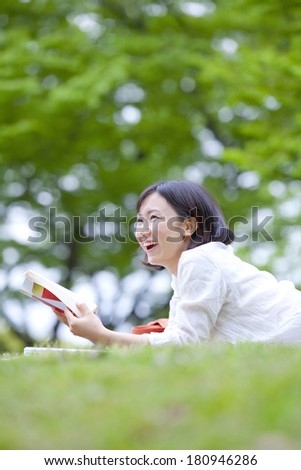 Japanese Students laying on grass while reading a novel,