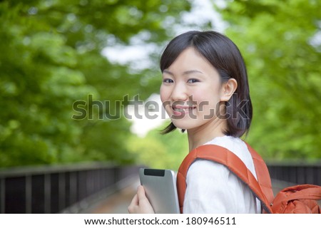A Japanese student looking back while holding a tablet PC,
