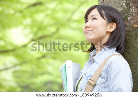 A Japanese student smiling surrounded by nature,