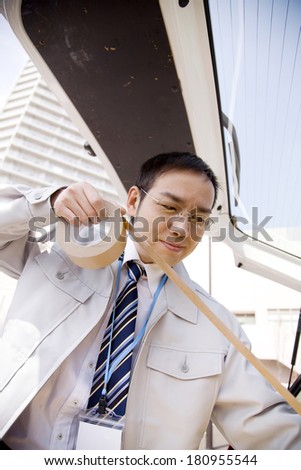 Japanese Businessman puts tape on a corrugated box