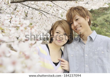 Couple snuggles up under cherry trees.