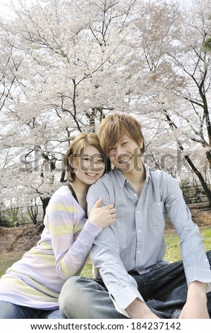 Couple snuggles up under a cherry tree.