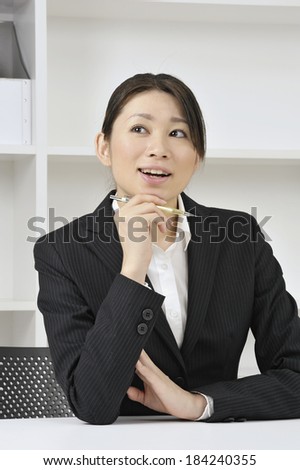 Japanese office woman sitting at desk daydreaming