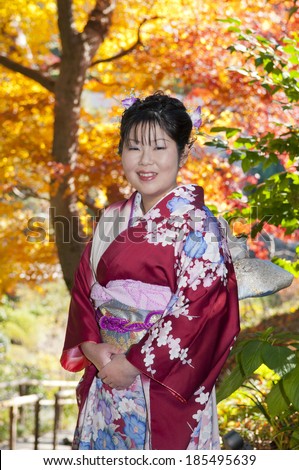 Asian woman enjoying fall at the park while dressed in traditional Japanese outfit