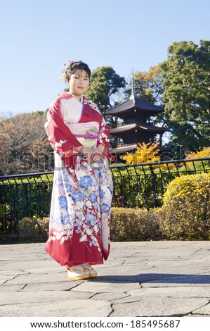 Asian woman standing in garden while dressed in traditional Japanese outfit