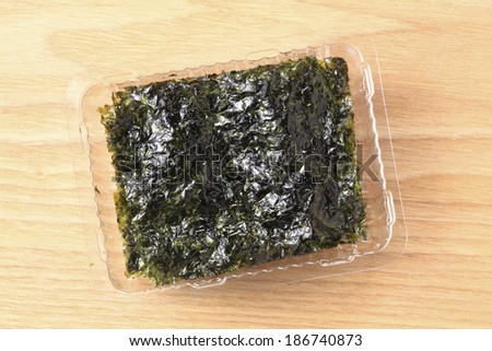 An image of Korean seaweed in plastic container on wood table