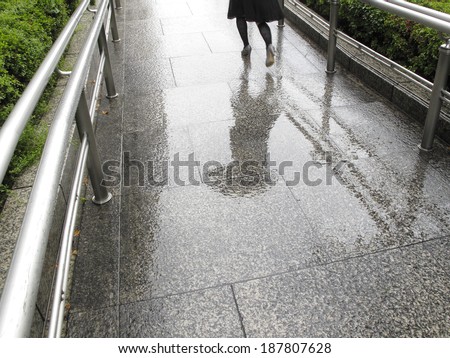 Woman running in heels during rainstorm on a slippery sloped pathway