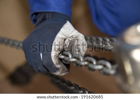 Hands of workers catching chain block