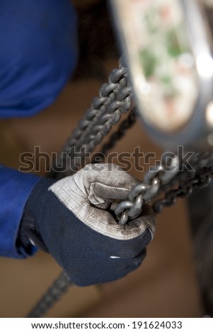 Hands of workers catching chain block