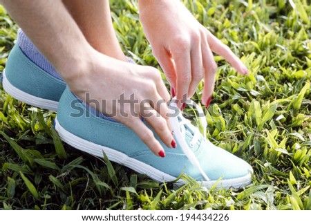 Hands of the woman lacing her shoe on the lawn