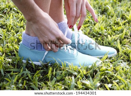 Hands of the woman lacing her shoe on the lawn