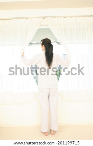 Woman opening the curtain