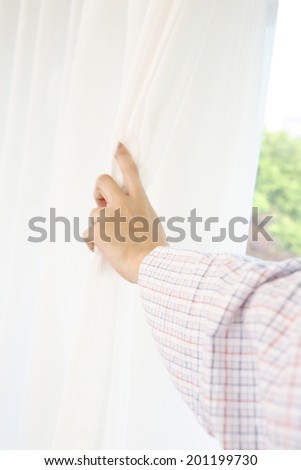 a hand of the woman opening the curtain