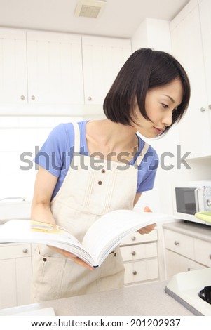 Woman cooking while watching the cookbook