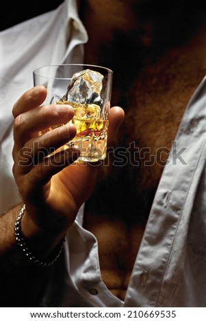 Chest And Hand Of A Man With Whiskey On The Rocks