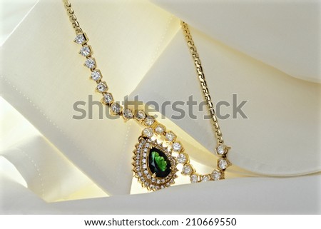 Emerald Pendant Decorated With Diamonds On A Silk Blouse