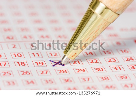 Close up of lottery ticket with a marked number and a pen
