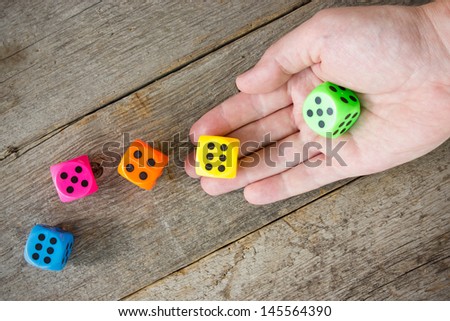 Hand throwing colorful dice  on the old wooden floor.