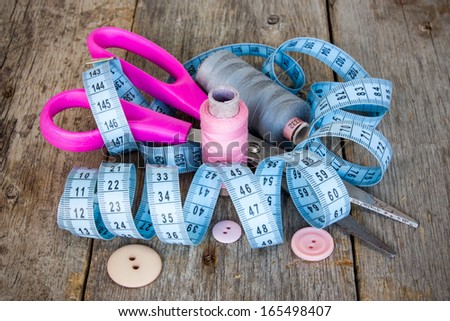 Tailor\'s tools. Scissors, measure tape, spools and buttons on the wooden floor.