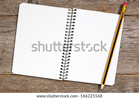 Spiral notebook and pencil on a wooden background