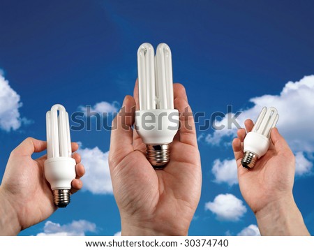 concept for energy saving. cf light bulbs in hands on sky background