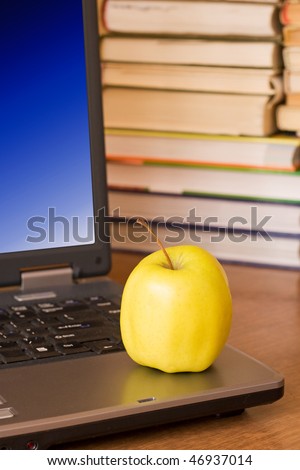 laptop with yellow apple on books background