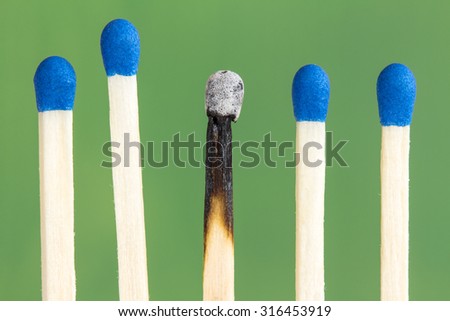 Row of match sticks with blue heads, over a green background