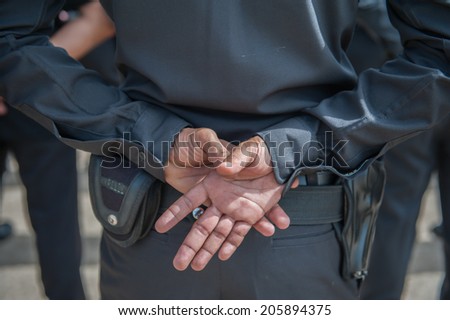 Standing with his hands on the back of the police.