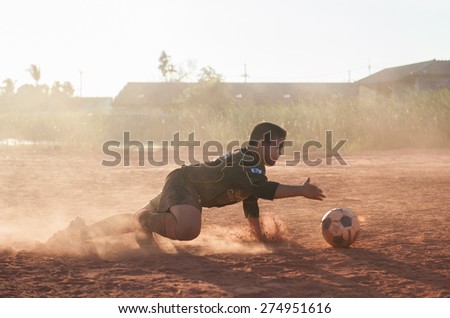 SURATTHANI THAILAND- Mar 25: Local kids enjoy playing football on dust field after school. Mar 25,2014 in suratthani province,Thailand