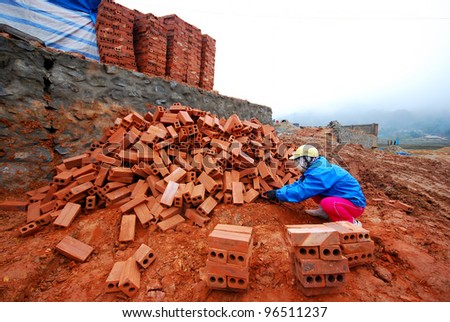 Man stack up bricks at construction site during winter cold weather