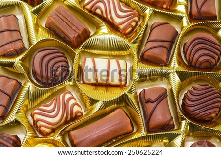 Box of  sweet chocolate candies displayed on shiny gold wrapping paper