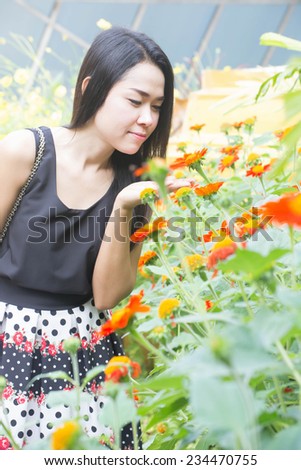 Photo of beautiful Asian woman in a flower garden, cute female enjoying smell of flower in the morning with the sun light, Thailand.